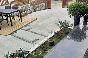 A patio area with a table and chairs, a small garden with plants, and a wooden deck.