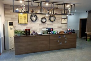 A reception desk with a wooden finish, a coffee machine, and various items on display. - Tianzhushan Motu Station Homestay (Qianshan)