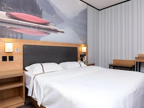 A hotel room with a bed, a nightstand, a wall-mounted lamp, and a mural of a mountain landscape. - Thank You Inn Beijing Huairou Yanqi (Huairou)