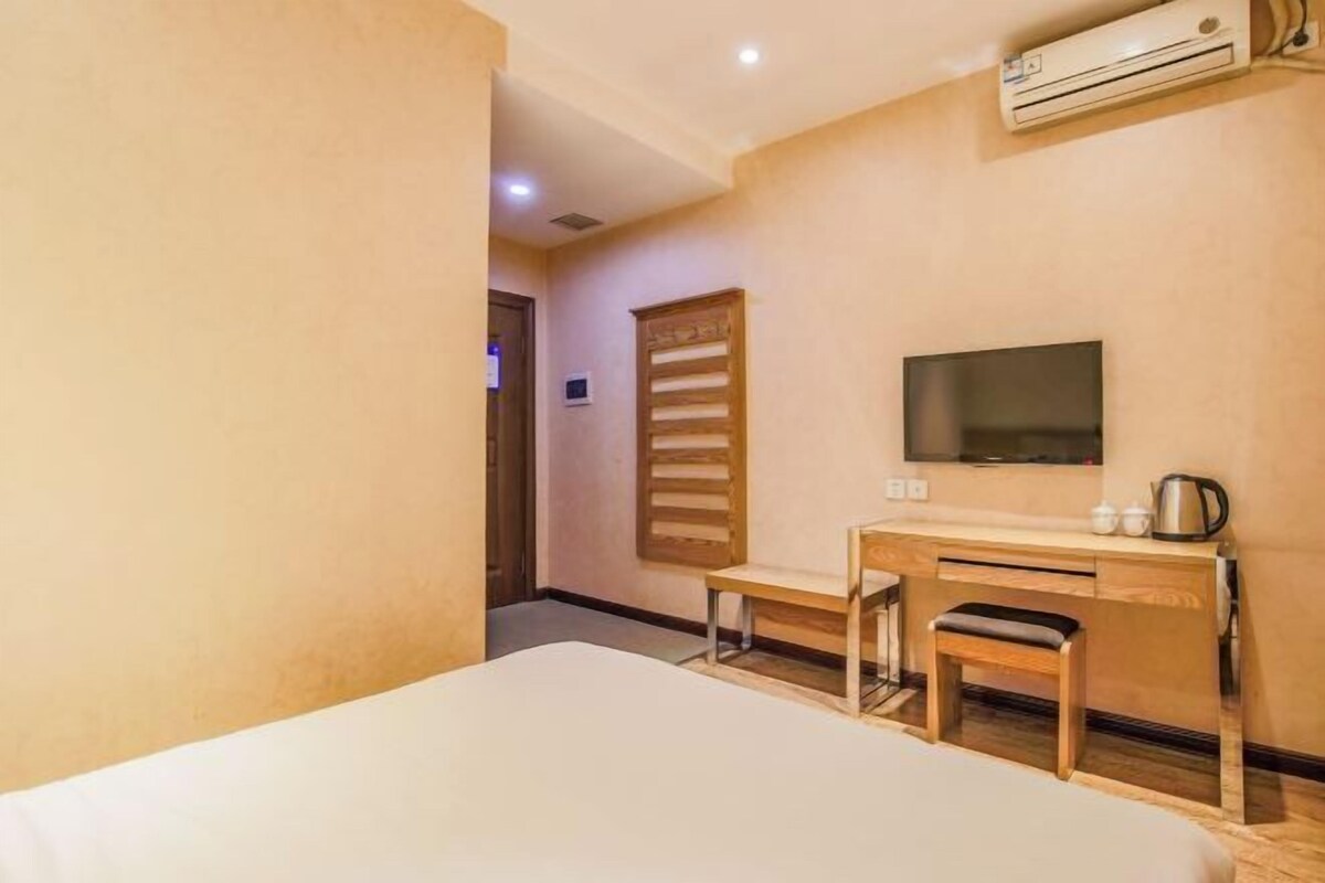 Une chambre d’hôtel équipée d’un lit, d’un bureau avec une chaise, d’une télévision et d’un appareil de climatisation.