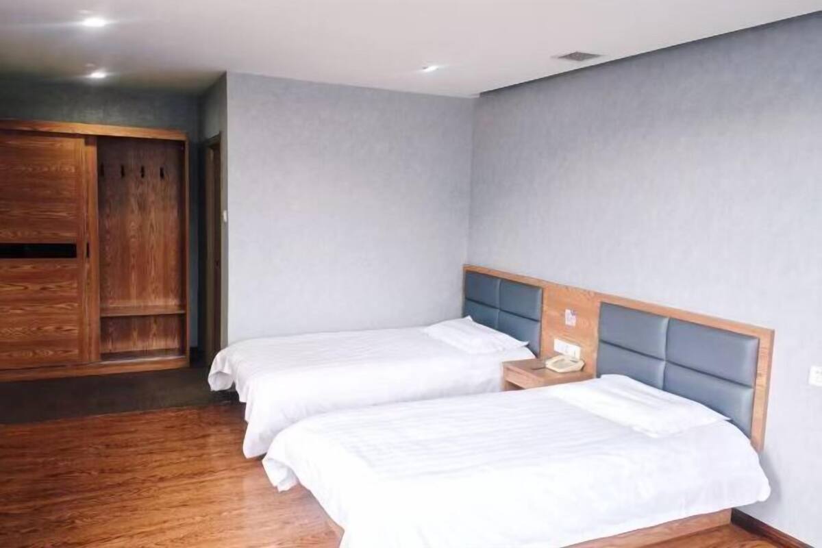 Ein Hotelzimmer mit zwei Betten, einem Holzschrank und einem Nachttisch mit Telefon.