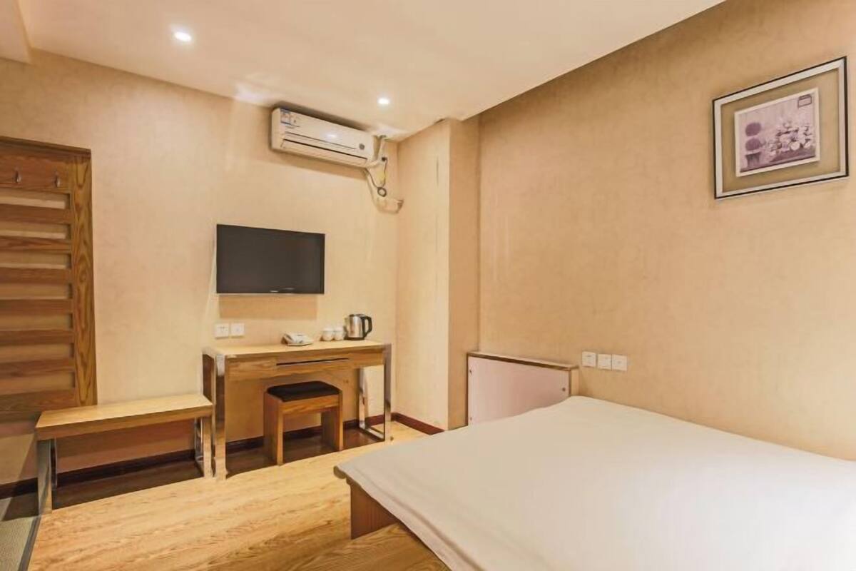 Ein Hotelzimmer mit Bett, Schreibtisch mit Stuhl, Fernseher und Klimaanlage.