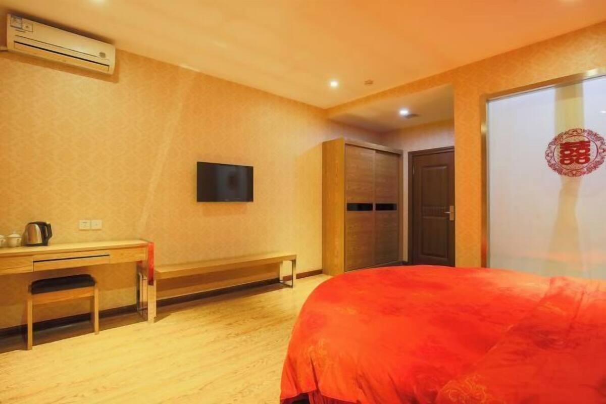 Ein Hotelzimmer mit einem Bett, einem Schreibtisch, einem Sessel, einem Fernseher und einem Kleiderschrank.