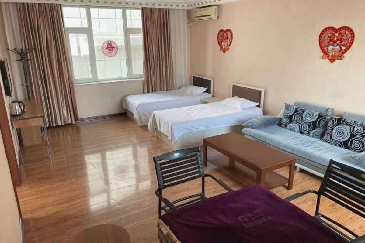Ein Hotelzimmer mit zwei Betten, einem Schlafsofa, einem Tisch und einem Stuhl.