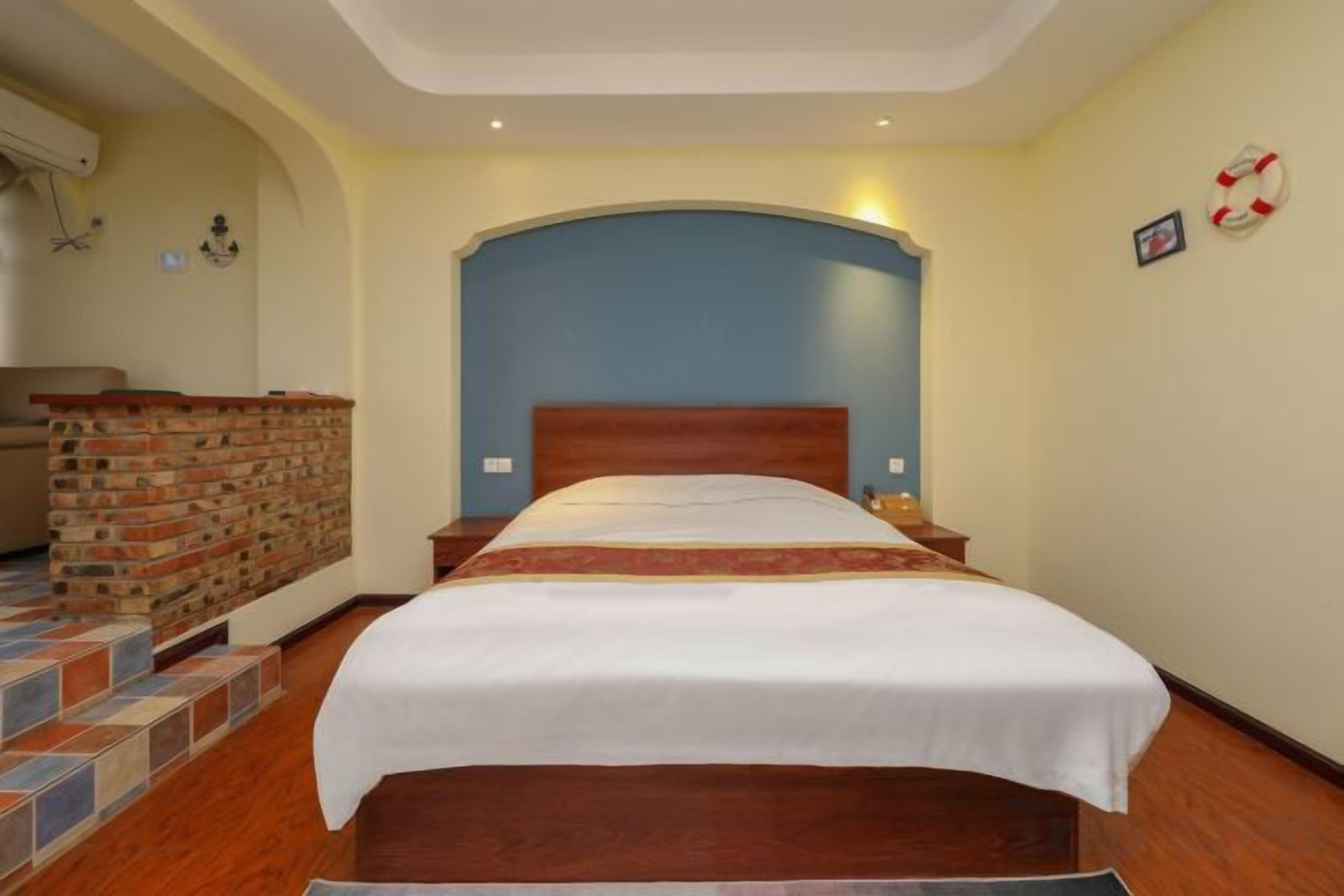 A hotel room with a large bed, a brick wall, and a blue accent wall.