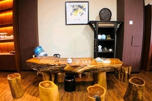 A wooden table with chairs, a shelf with teapots, and a framed picture on the wall. - Qianshan Yihao Villa (Yuxi)