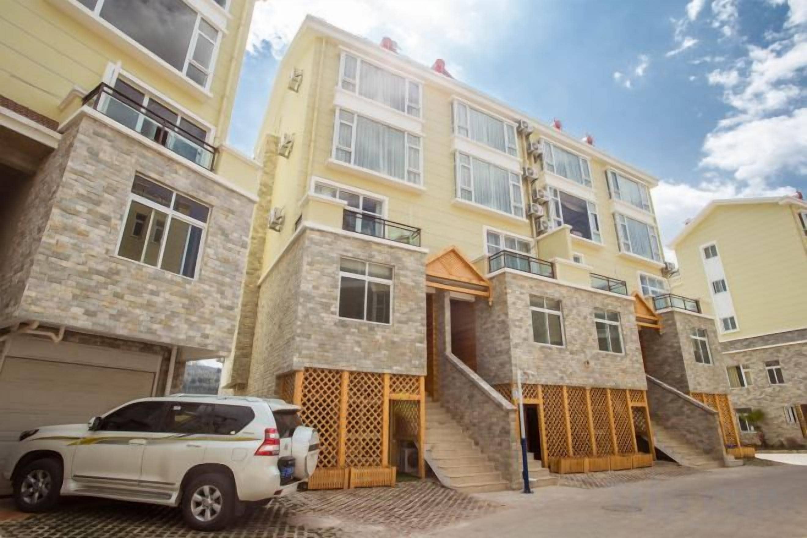 A multi-story residential building with a garage, a staircase, and a car parked in front.