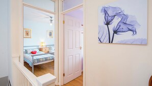 A bedroom with a bed, bedside table, and a wall-mounted painting. - Cwtch Cottage, Holiday Cottage Broad Haven, Sleeps 5, 3 bedrooms,  bathrooms (Haverfordwest)