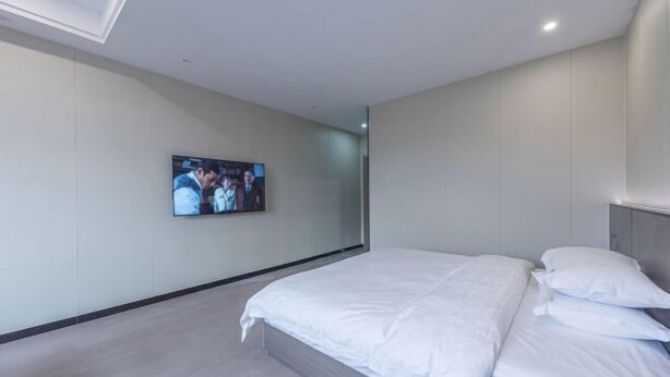 Een moderne hotelkamer met een groot bed, een flatscreen-tv aan de muur en een minimalistisch design.