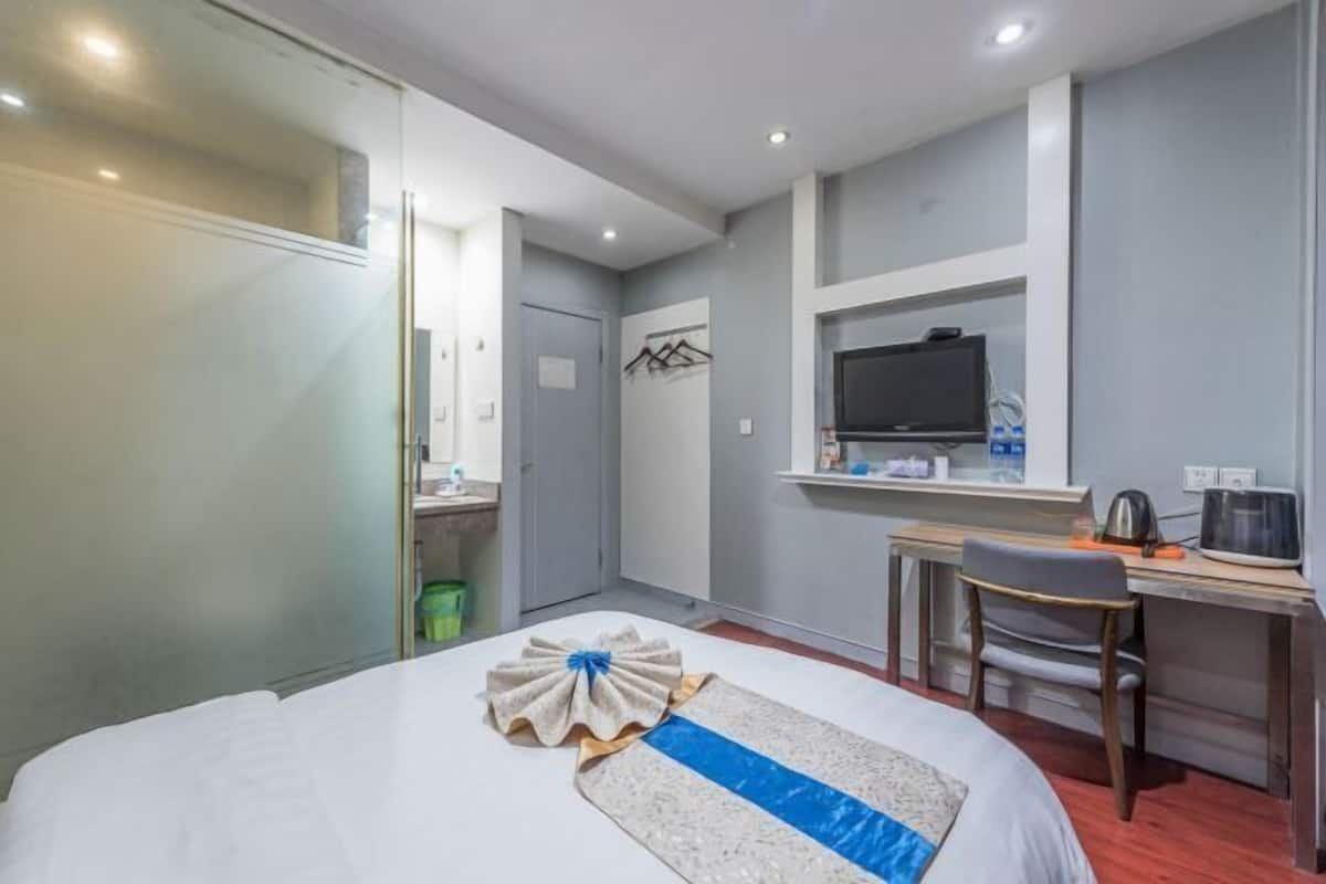 Une chambre d’hôtel équipée d’un lit, d’un bureau, d’une chaise, d’une télévision et d’une petite kitchenette.