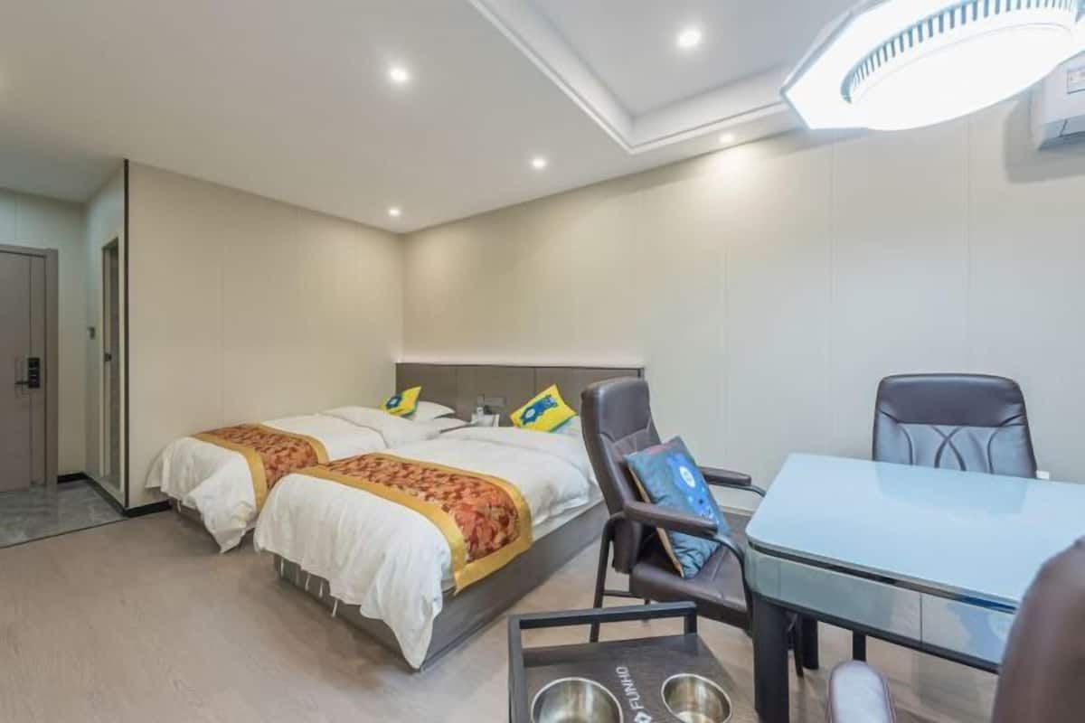 Une chambre d’hôtel avec deux lits, un bureau et une chaise.