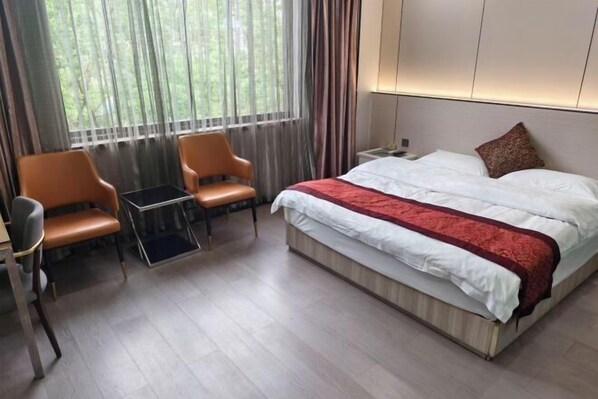 A hotel room with a bed, two chairs, a small table, and a window with curtains. - Tiansheng Hotel (Ningbo Lishe Airport) (Ningbo)