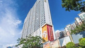 A tall, modern building with multiple floors, surrounded by smaller buildings and greenery. - City Posthouse (Shenzhen Buji Daduhui) (Shenzhen)