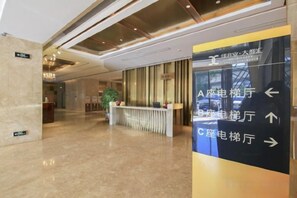 A hotel lobby with a reception desk, directional signs, and a plant. - City Posthouse (Shenzhen Buji Daduhui) (Shenzhen)