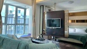 A hotel room with a large window, a flat-screen TV, a bunk bed, and a sofa. - City Posthouse (Shenzhen Buji Daduhui) (Shenzhen)