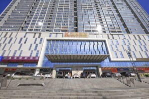 A modern building with a prominent entrance, multiple floors, and several parked cars in front. - City Posthouse (Shenzhen Buji Daduhui) (Shenzhen)