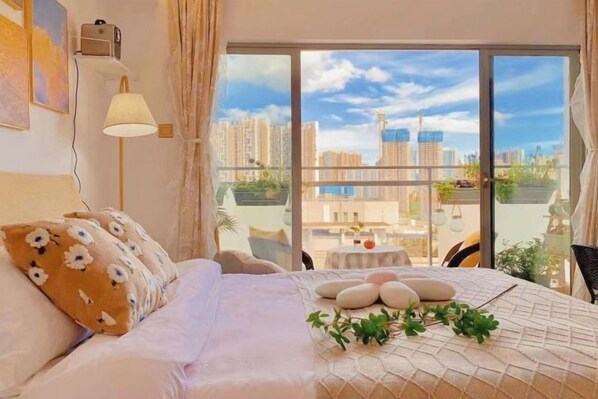 A hotel room with a large bed, a small table with decorative stones, and a view of the cityscape through large windows. - City Posthouse (Shenzhen Buji Daduhui) (Shenzhen)