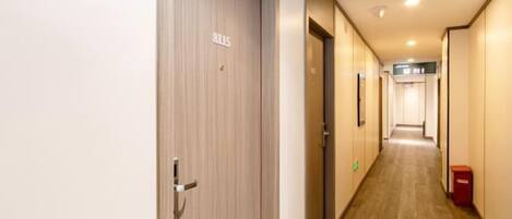 A hotel hallway with a wooden floor, a door marked '8015', and a trash bin on the right.