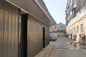 Een smalle steeg met een gebouw aan één kant en geparkeerde auto's aan de andere kant.