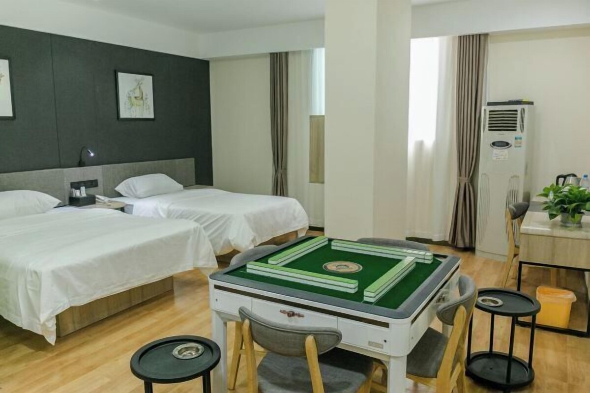 Habitación de hotel con dos camas, una mesa de billar, un escritorio con silla y un equipo de aire acondicionado.