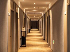 Un pasillo largo y estrecho en un hotel, con alfombra y puertas a ambos lados.