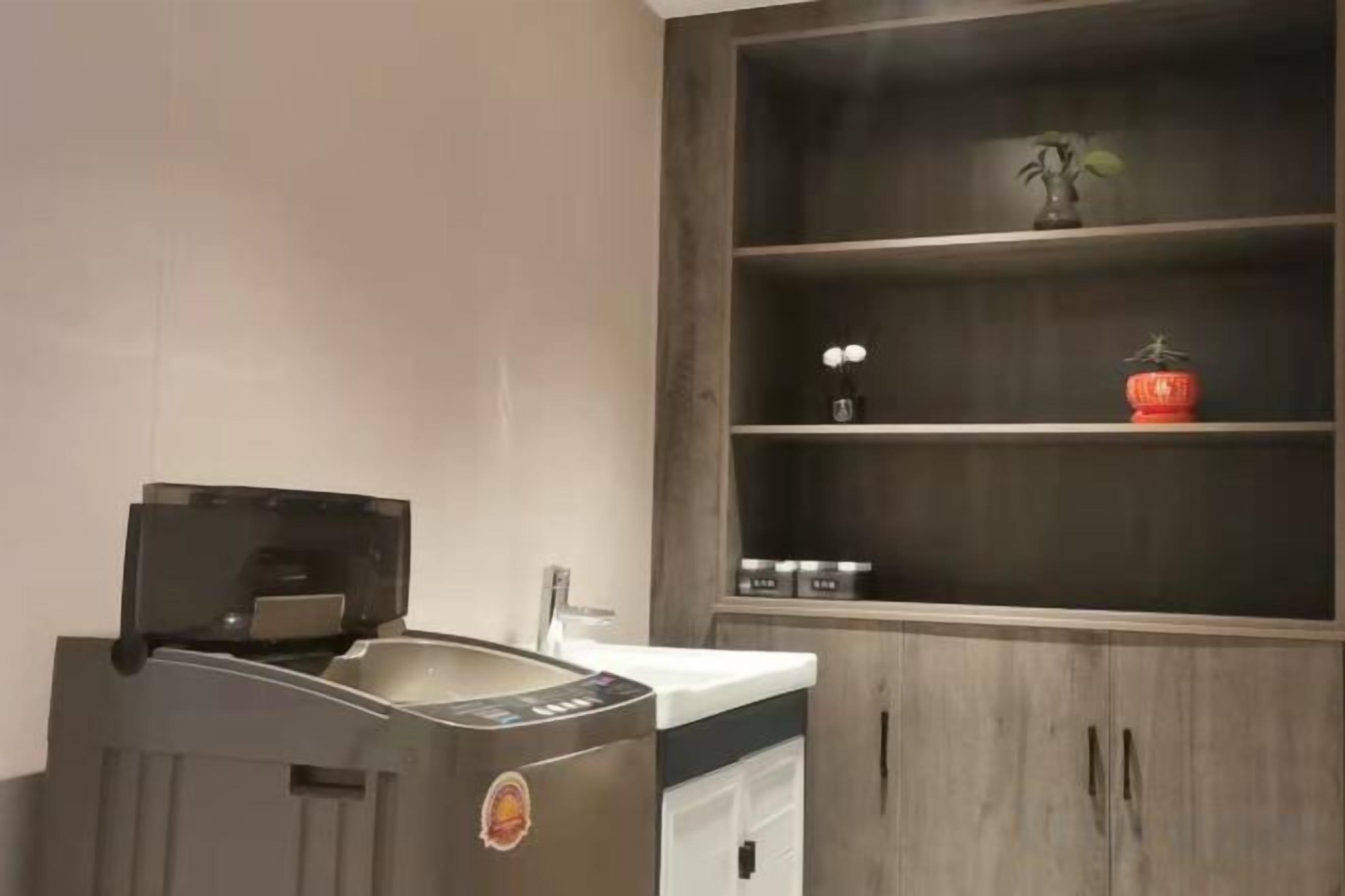A kitchen with a built-in coffee machine, a sink, and a wooden cabinet with shelves.
