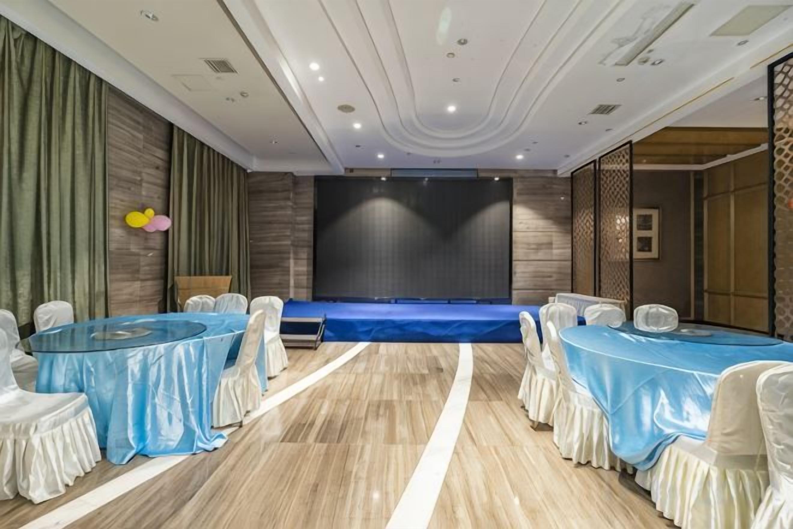 A conference room with a stage, round tables, and chairs.