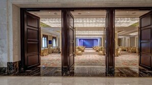 A hotel lobby with a marble floor, a large seating area with round tables and chairs, and a blue curtain backdrop. - Bon Delight Hotel (Hefei)