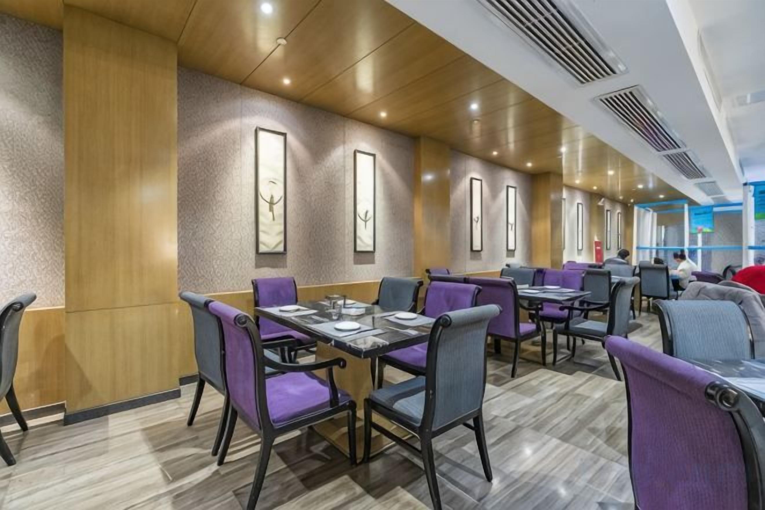 A modern dining area with tables and chairs, wooden paneling, and artwork on the walls.