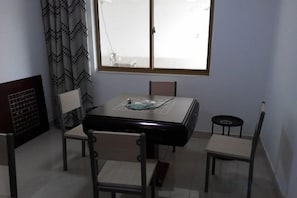A dining area with a table and four chairs, a window with curtains, and a radiator. - Jinze Farm House (Shanghai)