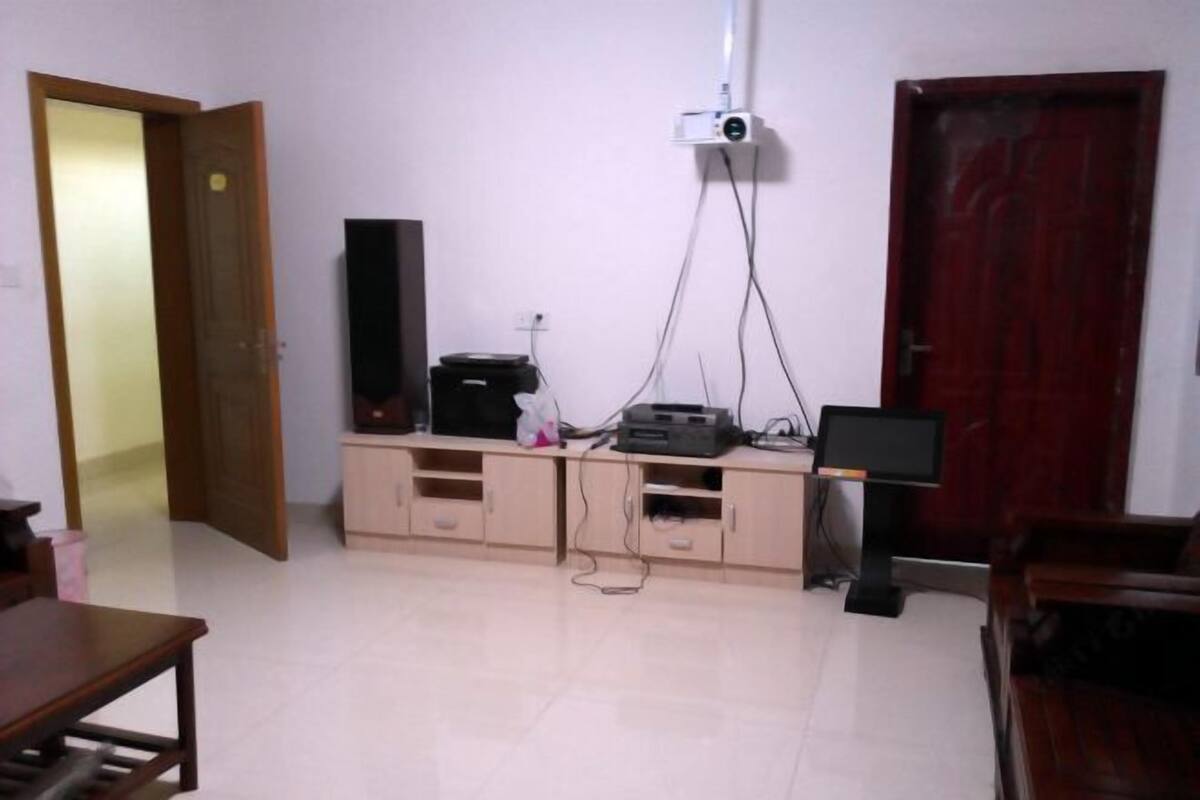 Una habitación con un armario de madera, un televisor de pantalla plana, un proyector y una puerta roja.