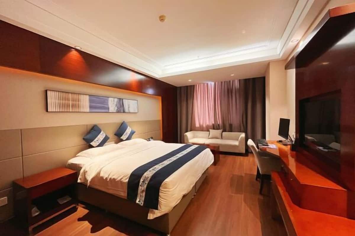 Ein Hotelzimmer mit einem Bett, einem Sofa, einem Schreibtisch mit Computer und einem Fernseher.