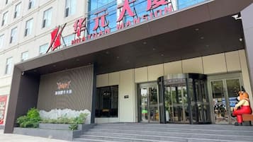 A hotel entrance with a modern facade, glass doors, and a sign with Chinese characters.