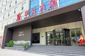 A hotel entrance with a modern facade, glass doors, and a sign with Chinese characters. - Chengcheng Huayuan Building (Chengcheng)