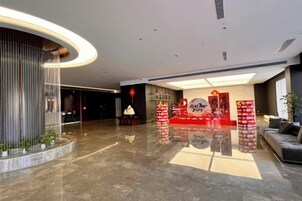 Un vestíbulo amplio con un mostrador de recepción curvo, una zona de estar y un gran panel iluminado en la pared.