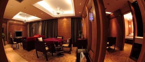 A hotel room with a curved ceiling, a chandelier, a red sofa, a desk, and a bed.
