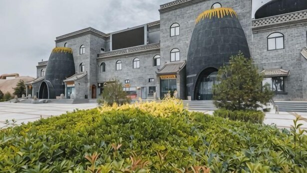 A building with a unique architectural style, featuring large, rounded structures on the roof, a paved courtyard, and a well-maintained garden area. - Chengcheng Huayuan Building (Chengcheng)