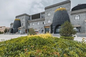 A building with a unique architectural style, featuring large, rounded structures on the roof, a paved courtyard, and a well-maintained garden area. - Chengcheng Huayuan Building (Chengcheng)