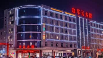 A multi-story hotel with a curved facade, illuminated signage, and a prominent entrance.