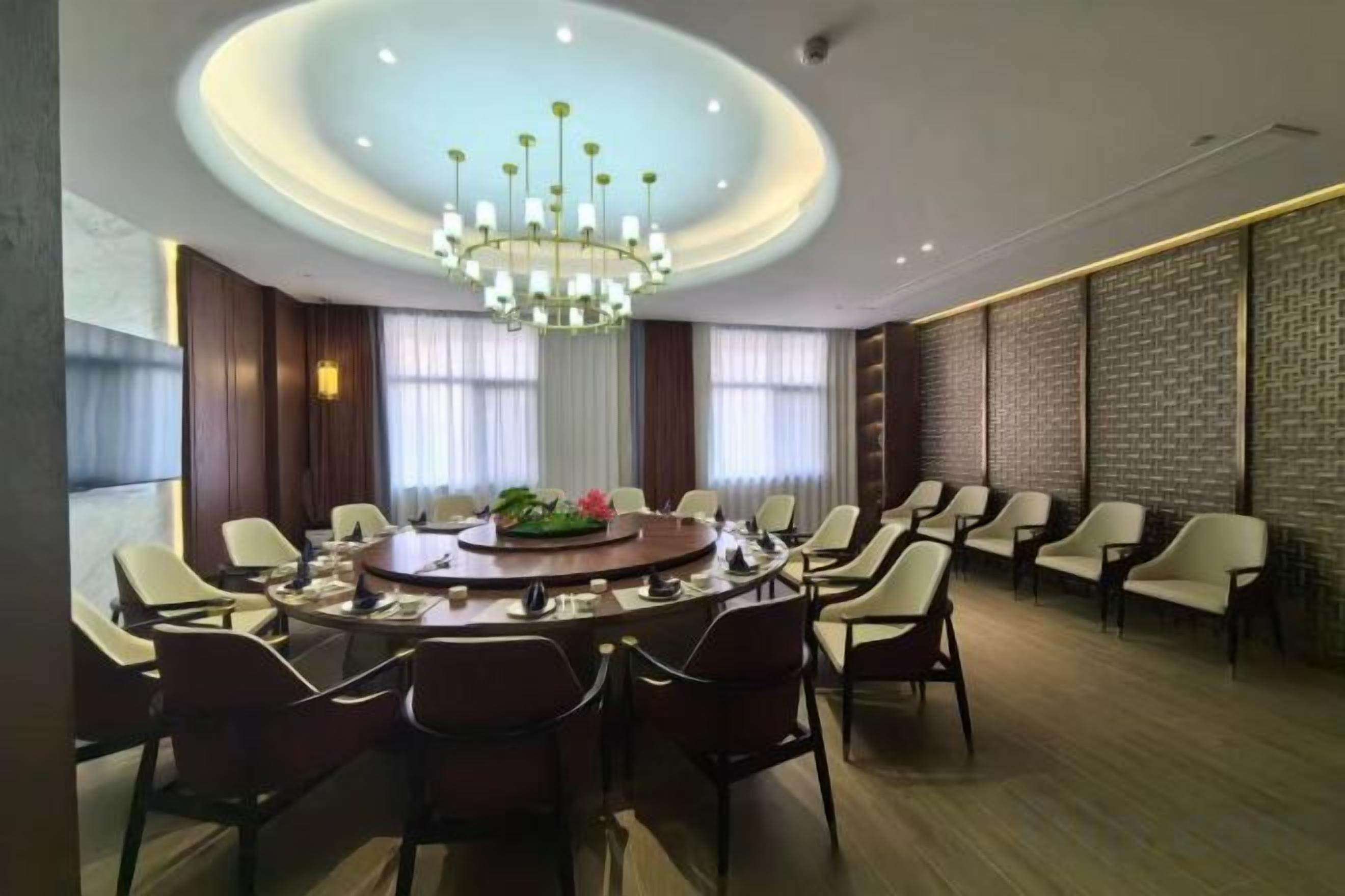 A conference room with a round table, chairs, a chandelier, and a patterned wall.