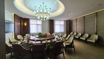 A conference room with a round table, chairs, a chandelier, and a patterned wall.