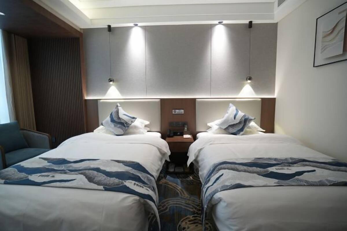 Ein Hotelzimmer mit zwei Betten, einem Schreibtisch, einem Stuhl und einem Nachttisch.