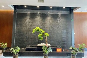 A reception area with a black wall, a water feature, and potted plants. - Chengcheng Huayuan Building (Chengcheng)