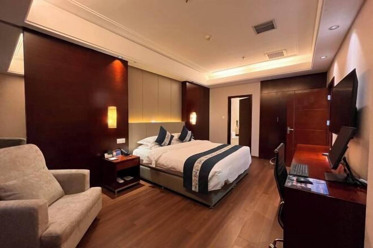 Ein Hotelzimmer mit Bett, Schreibtisch, Stuhl und Fernseher.