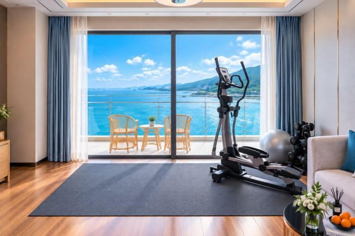 A room with a large sliding glass door leading to a balcony with a view of the sea.
