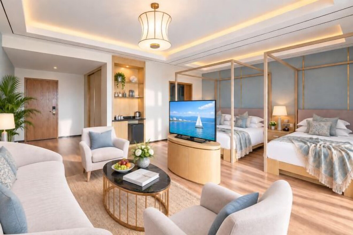 A modern hotel room with a sofa, a coffee table, a TV, a bed, and a balcony with a view.