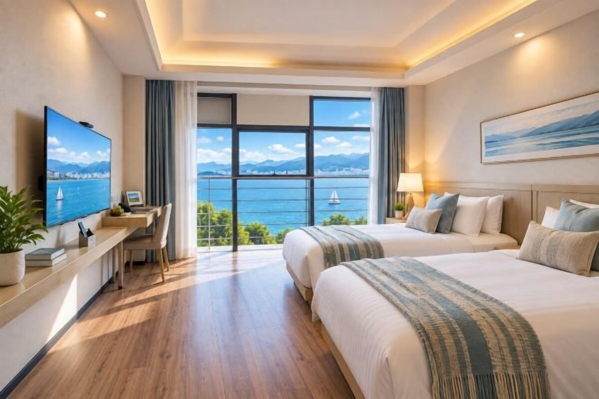 A hotel room with a large window, a desk, two beds, and a TV.