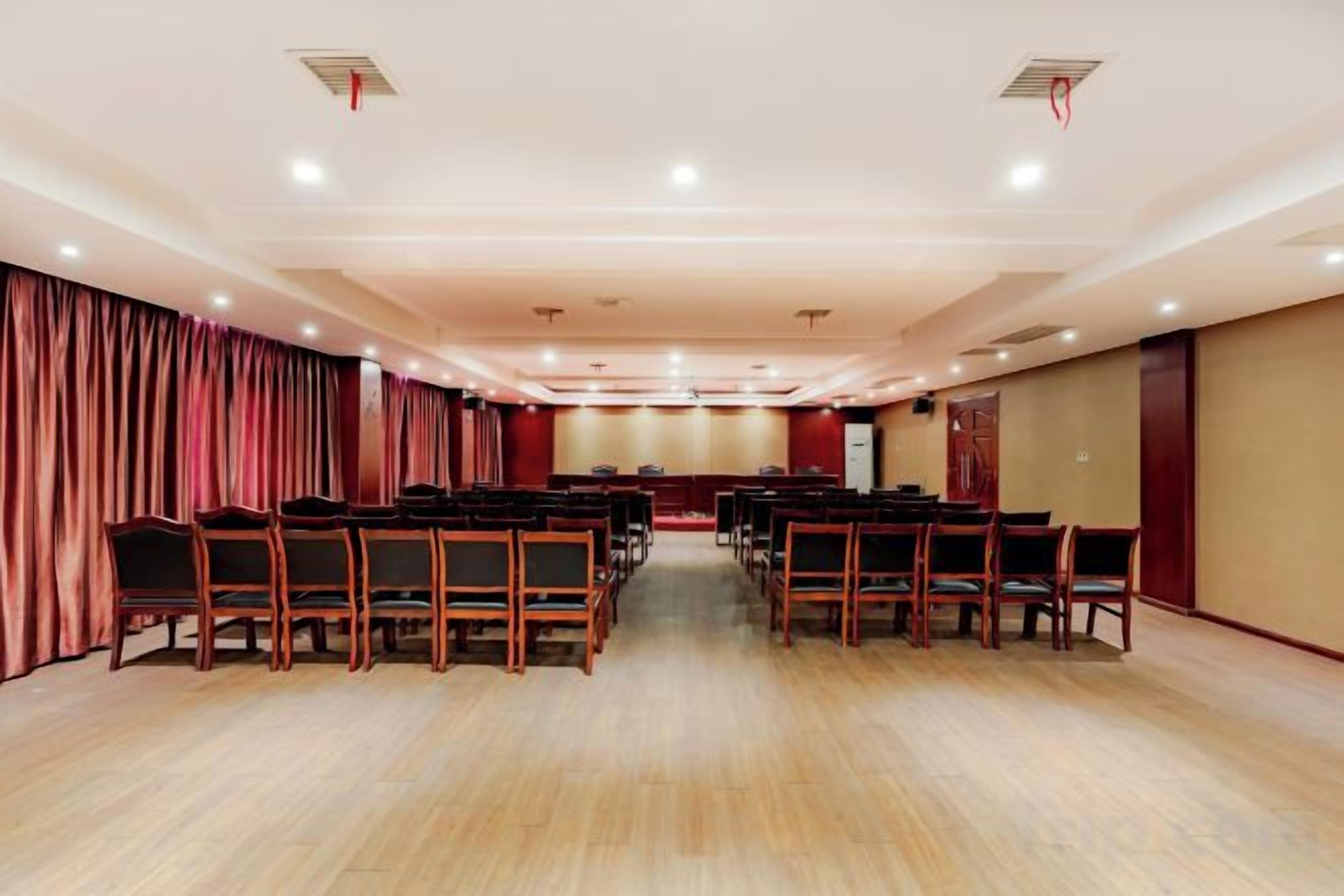 A conference room with rows of chairs, a stage, and curtains.
