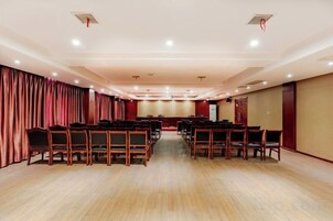 Un salón de conferencias con filas de sillas, un escenario y cortinas.