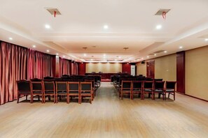 A conference room with rows of chairs, a stage, and curtains.